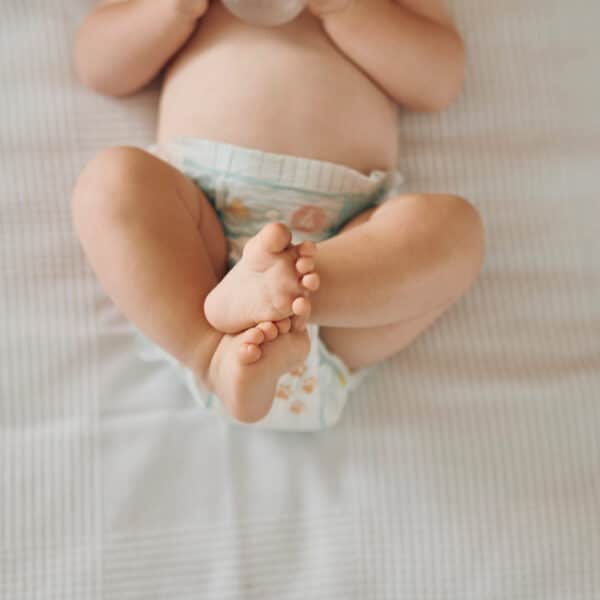 Beba leži s podignutim i prekriženim nogama, zatvor